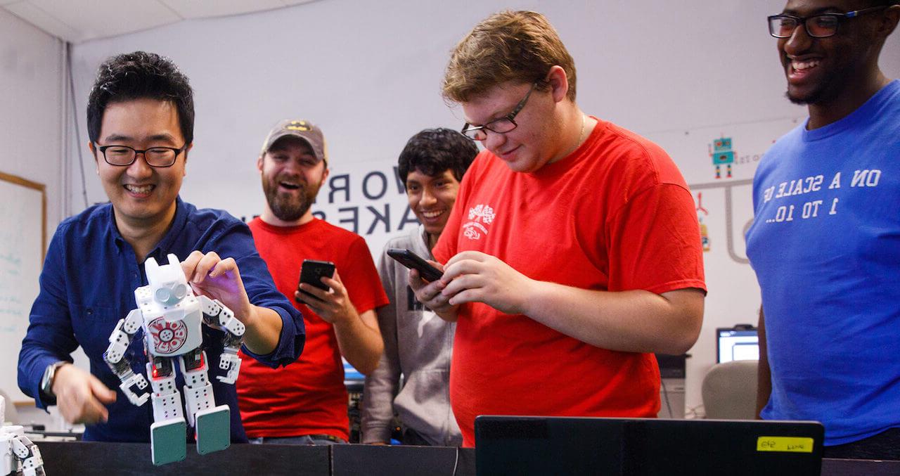 Students holding controls and a robotic character